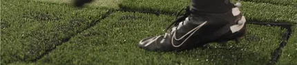 Person stepping on artificial turf with black sports shoes Close-up of a person wearing black sports shoes stepping on artificial turf