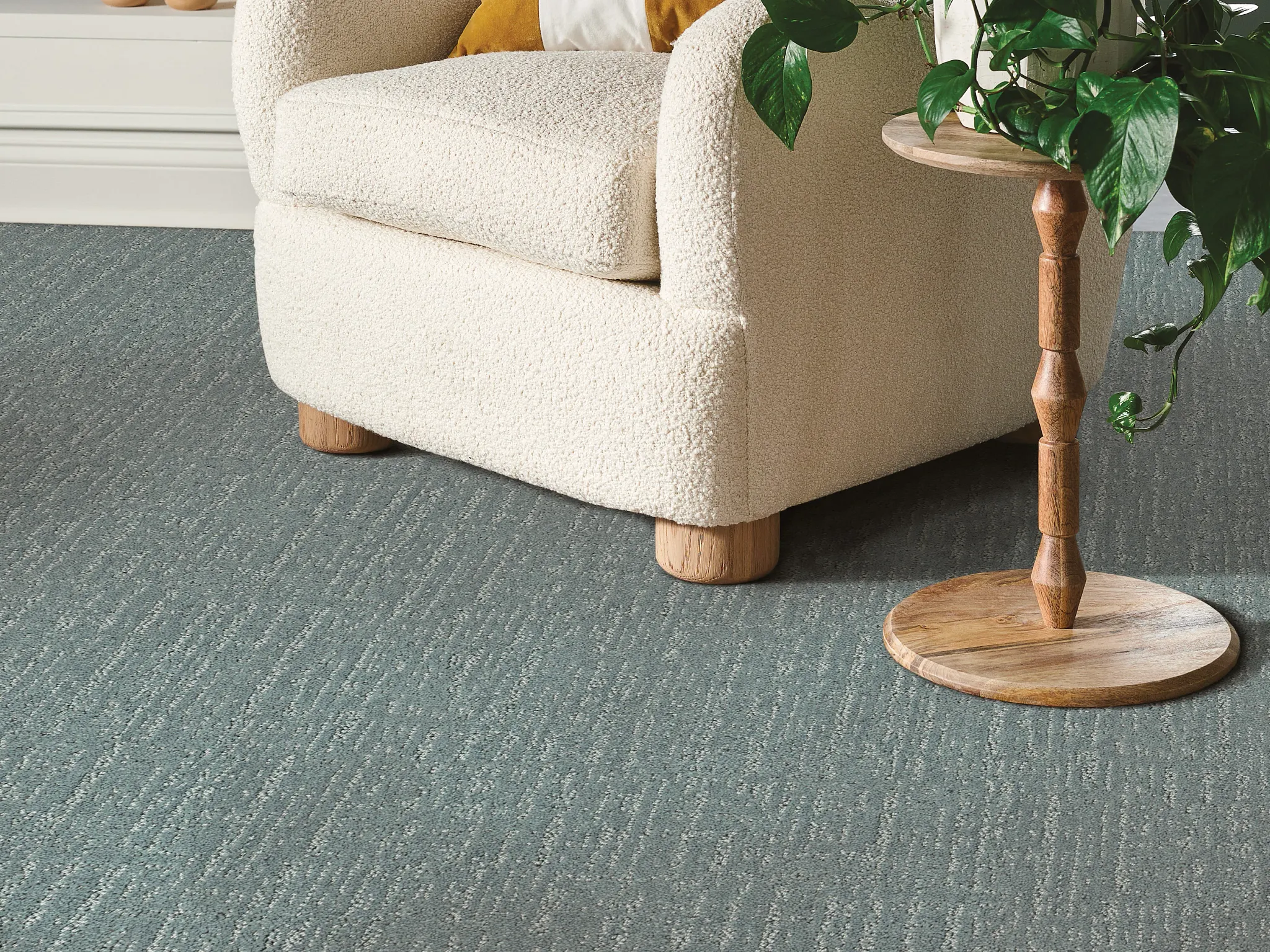 Cozy living room with a plush cream armchair and a wooden side table on a textured blue carpet