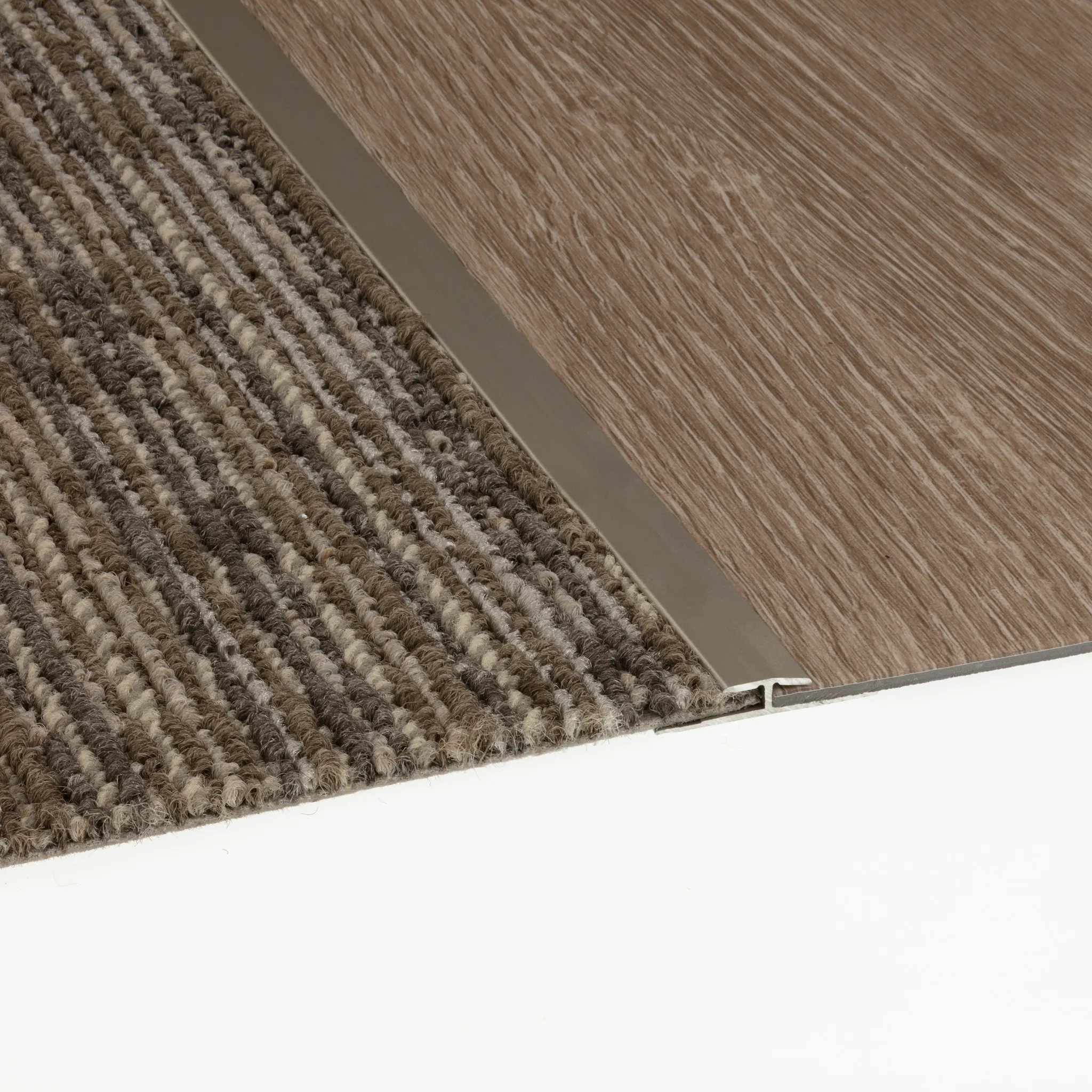 Close-up of commercial carpet tile in brown and beige stripes transitioning to wood-look commercial LVT with metal trim
