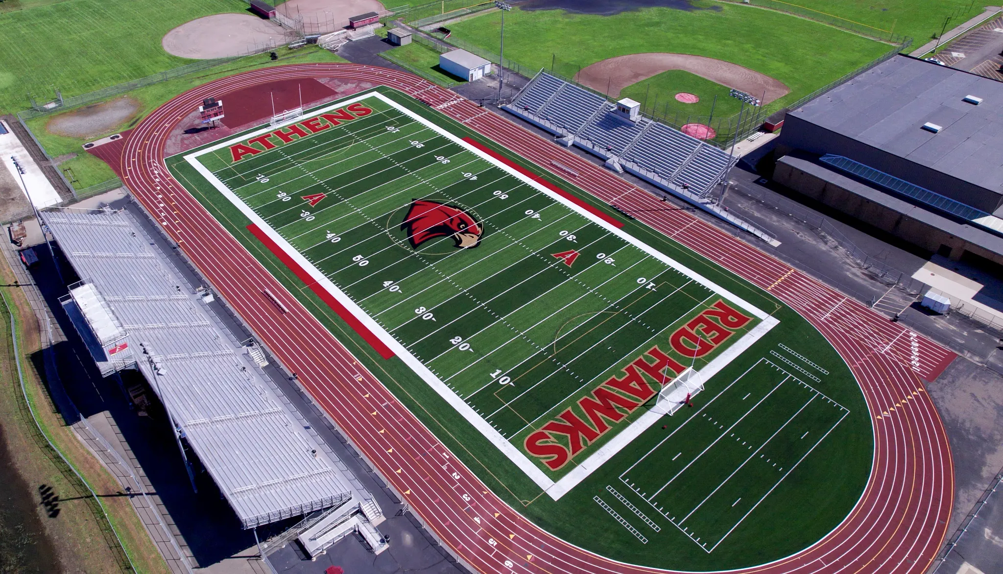 Aerial view of a sports stadium with artificial turf football field and running track