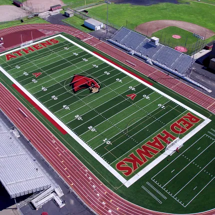 Artificial Turf Football Field and Running Track Stadium Aerial View Aerial view of a sports stadium with artificial turf football field and running track