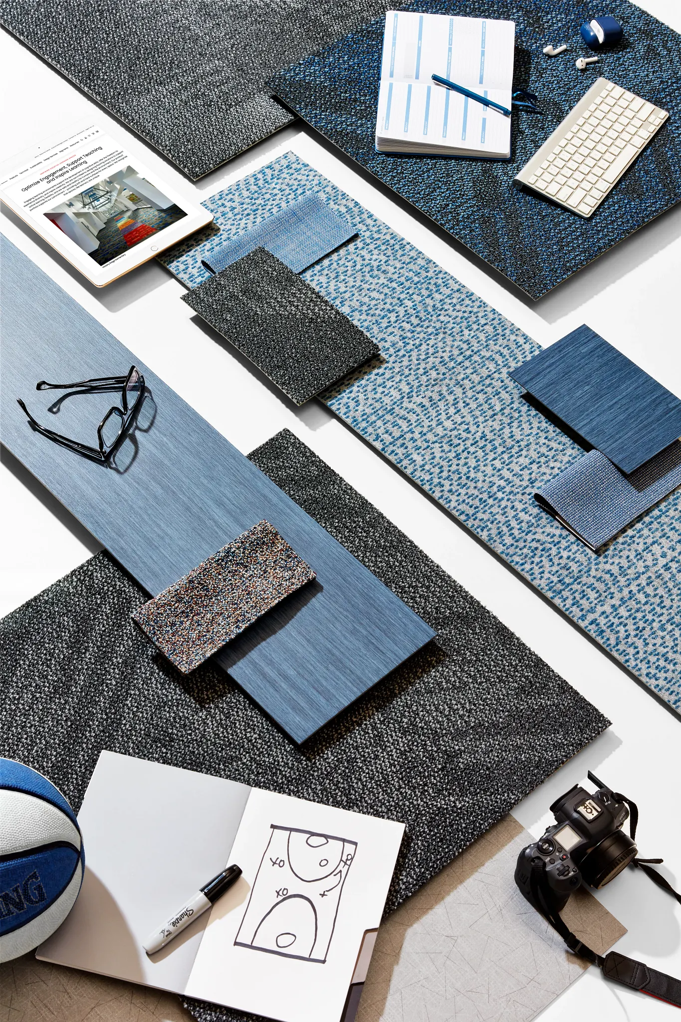 Assorted flooring swatches in shades of blue and gray with office supplies and a basketball