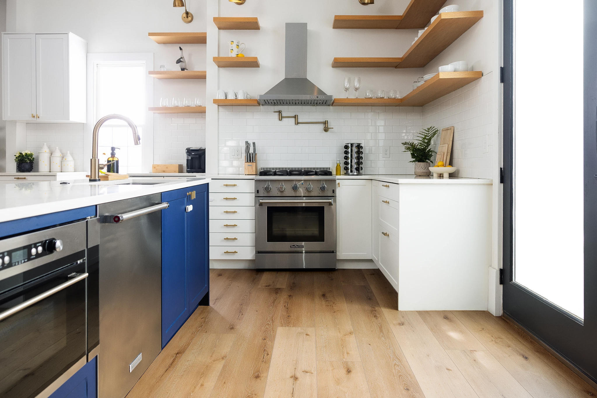 kitchen with luxury vinyl plank floor in a wood look with blue cabinets and stainless steel appliances