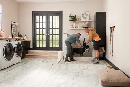 Durable Tile Flooring in a Practical Laundry Room Setting Modern laundry room with durable tile flooring and two men washing a dog