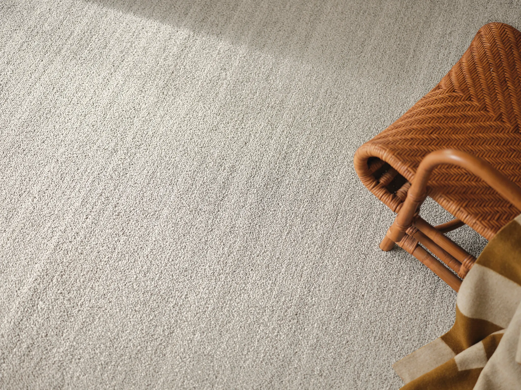 Beige carpet flooring with woven chair and blanket