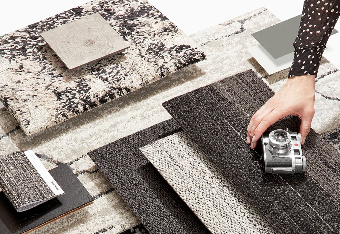 Commercial Carpet Tile Swatches in Black, White, and Gray Assorted commercial carpet tile swatches in shades of black, white, and gray with a hand holding a camera
