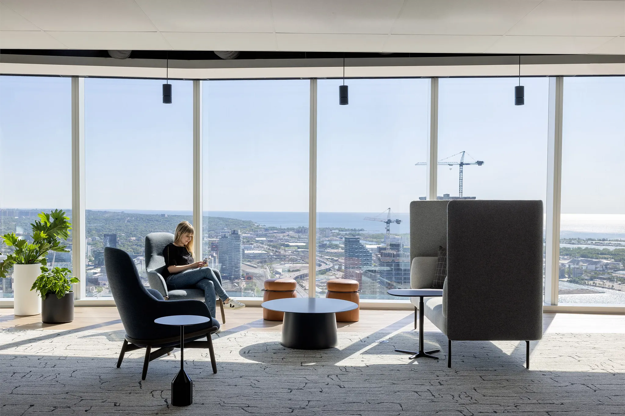 Modern office lounge with large windows and city view, featuring contemporary furniture and textured flooring