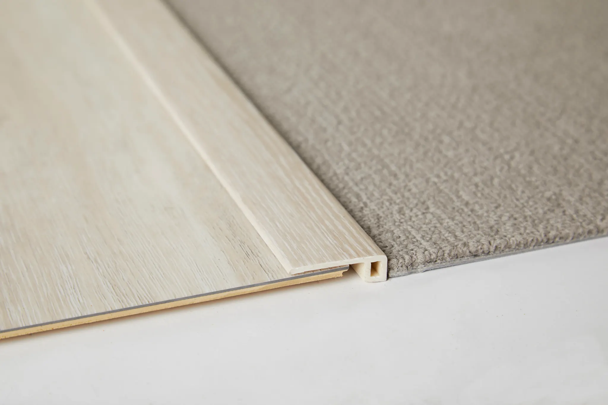 Close-up of beige carpet and light wood flooring transition