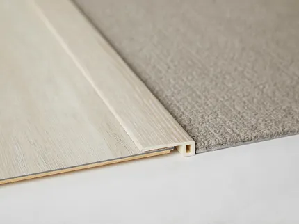 Seamless transition between carpet and wood flooring Close-up of beige carpet and light wood flooring transition