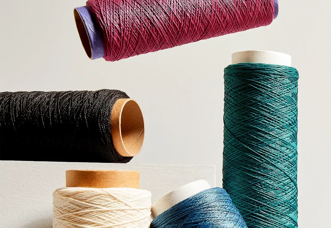 Spools of yarn in various colors including red, black, cream, blue, and teal