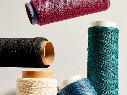 Colorful yarn spools for textile production Spools of yarn in various colors including red, black, cream, blue, and teal