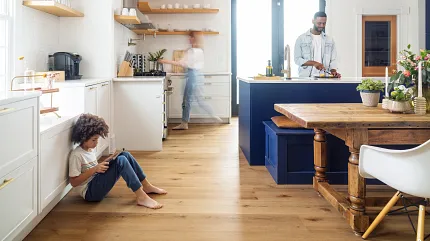 Coretec Residential SPC LVP Flooring in Modern Kitchen - 72.83x9.06 inch Modern kitchen with Coretec Residential SPC luxury vinyl plank flooring in a wood look, featuring a young child sitting on the floor and adults in the background
