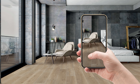 Person holding a mobile phone to view their room with a new floor visualized.