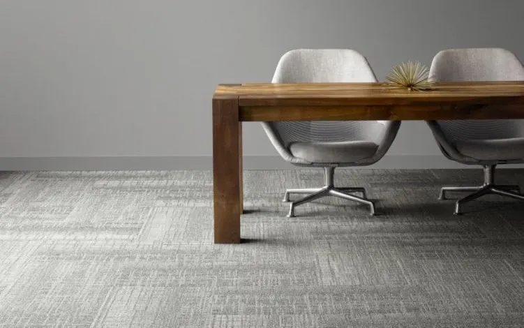 Modern office setting with gray carpet flooring, wooden table, and two gray chairs
