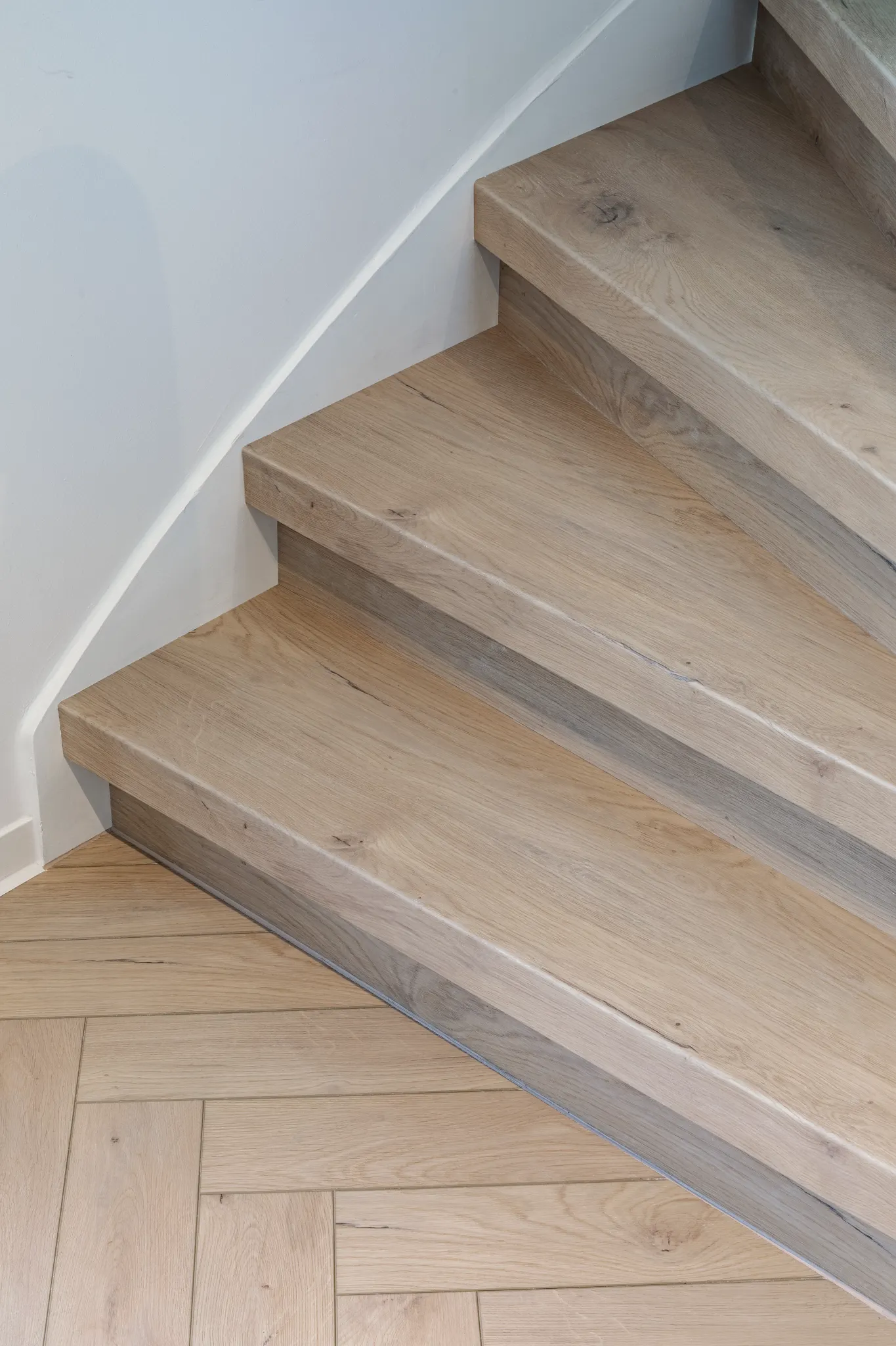 Close-up natural light wooden stairs and herringbone floor from Coretec