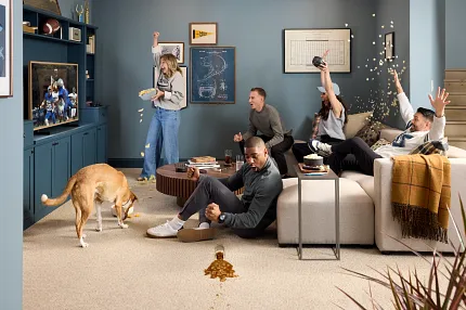 Comfortable and Durable Carpet Flooring for a Cozy Home Environment Cozy living room scene with a group of people enjoying a game on TV, featuring durable and easy-to-clean carpet flooring ideal for everyday lifestyle and comfort