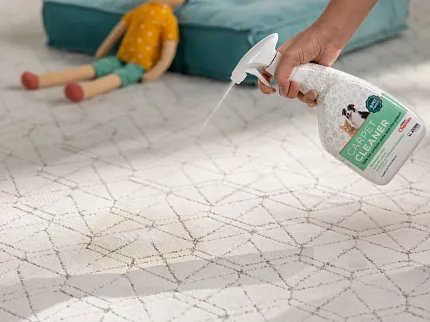 Easy-to-clean patterned carpet for everyday comfort and durability Hand spraying carpet cleaner on patterned carpet with geometric design