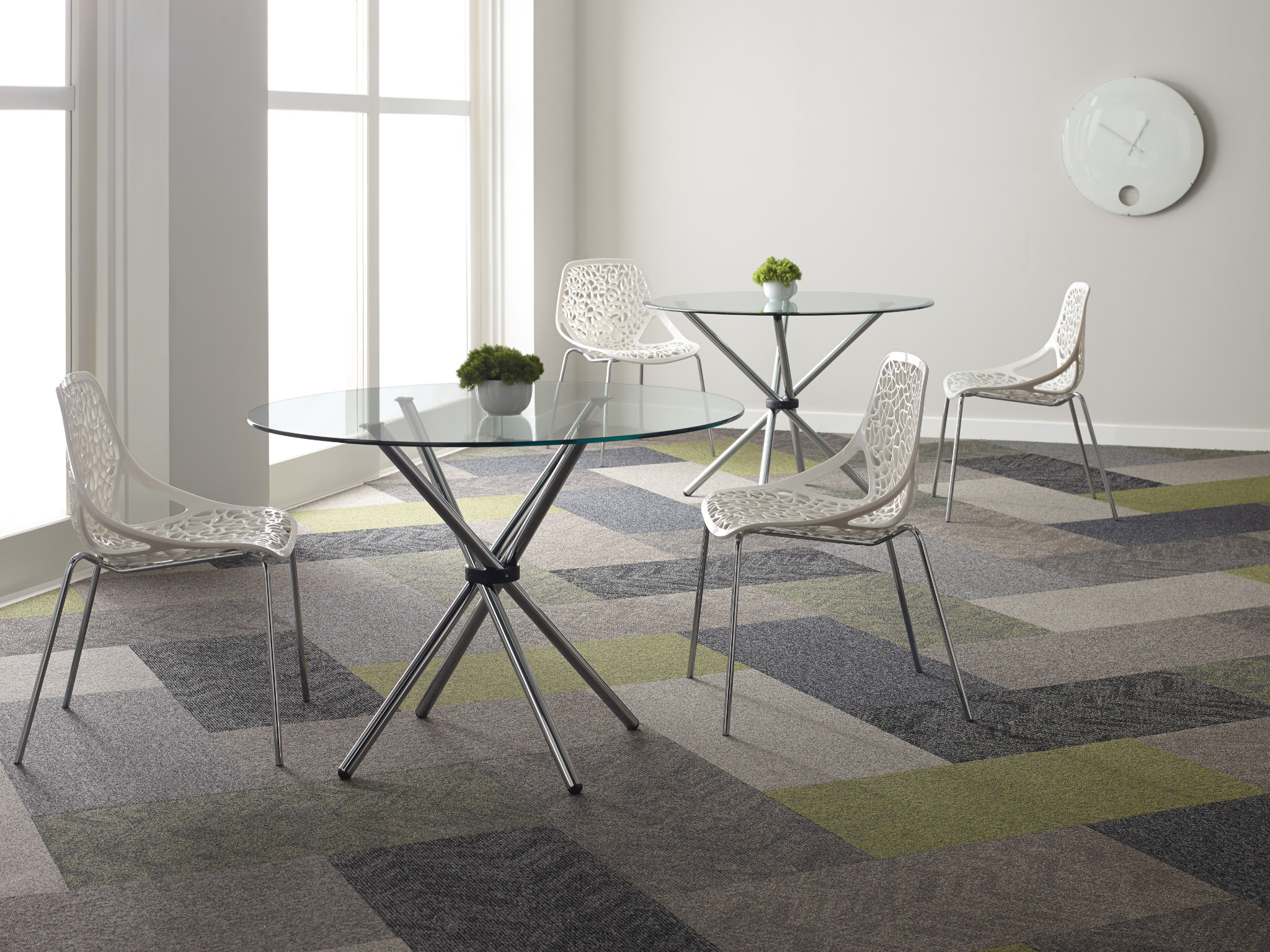 
  "office space with geometric patterned carpet tiles in shades of gray green and beige with glass tables and white chairs"
)