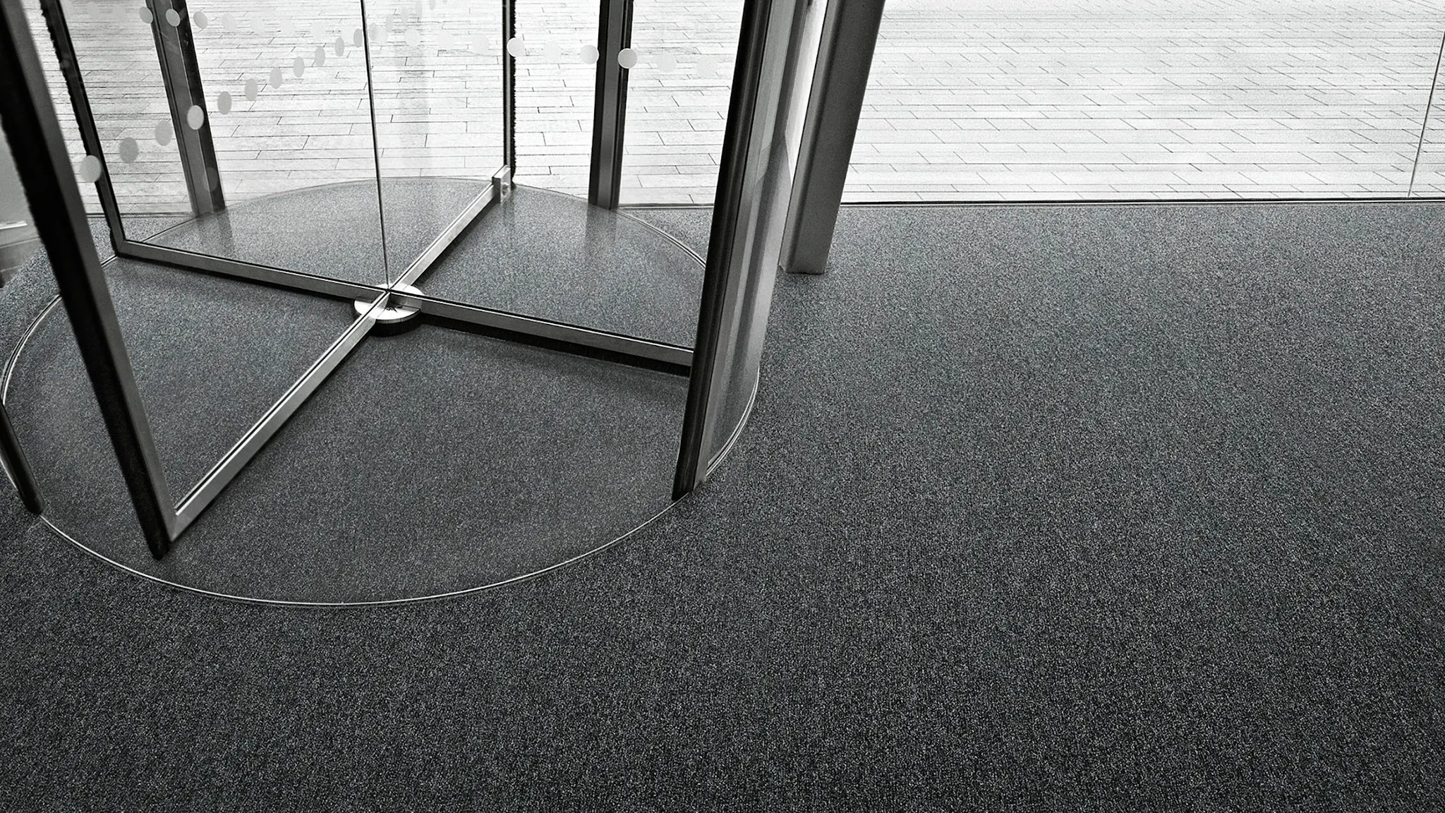 Modern entrance with revolving glass door and dark gray commercial carpet tile flooring