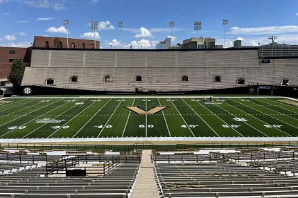 Artificial Turf Football Stadium with Empty Bleachers Football stadium with artificial turf field and empty bleachers under a clear blue sky