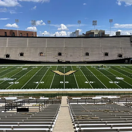 Artificial Turf Football Stadium with Empty Bleachers Football stadium with artificial turf field and empty bleachers under a clear blue sky