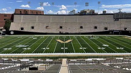Artificial Turf Football Stadium with Empty Bleachers Football stadium with artificial turf field and empty bleachers under a clear blue sky