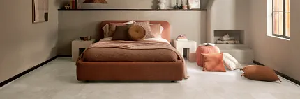 Coretec Mineral Core Residential LVT Flooring in Bedroom - 23.62x11.81 inch Modern bedroom with Coretec Mineral Core Residential luxury vinyl tile flooring in a light stone look, featuring a cozy bed and warm decor