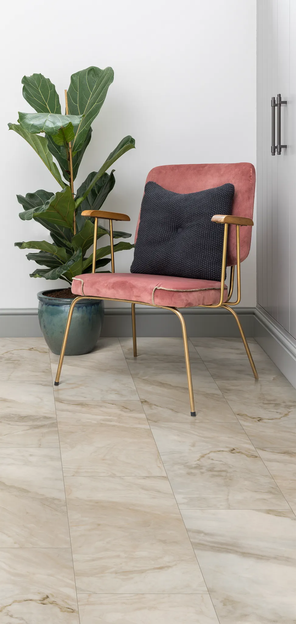 living room with beige marble tile floor with a pink velvet chair with a black cushion and a green potted plant