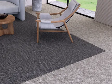 Terra Tile from the Core Elements Collection in Commercial Lounge Setting | Shaw Contract Australia Terra Tile carpet tile from the Core Elements collection by Shaw Contract installed in a contemporary commercial lounge featuring a curved sofa, timber lounge chair, round coffee table and floor-to-ceiling windows with views of landscaped greenery.