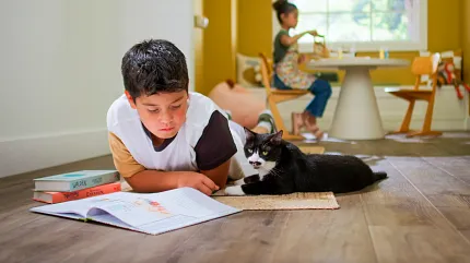 Wood Look Luxury Vinyl Plank Flooring in a Family Room Scene Child reading with a cat on wood look luxury vinyl plank flooring in a bright room