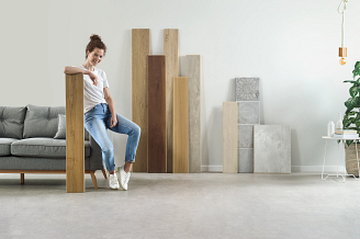 A woman sitting on a sofa in a room with vinyl flooring samples