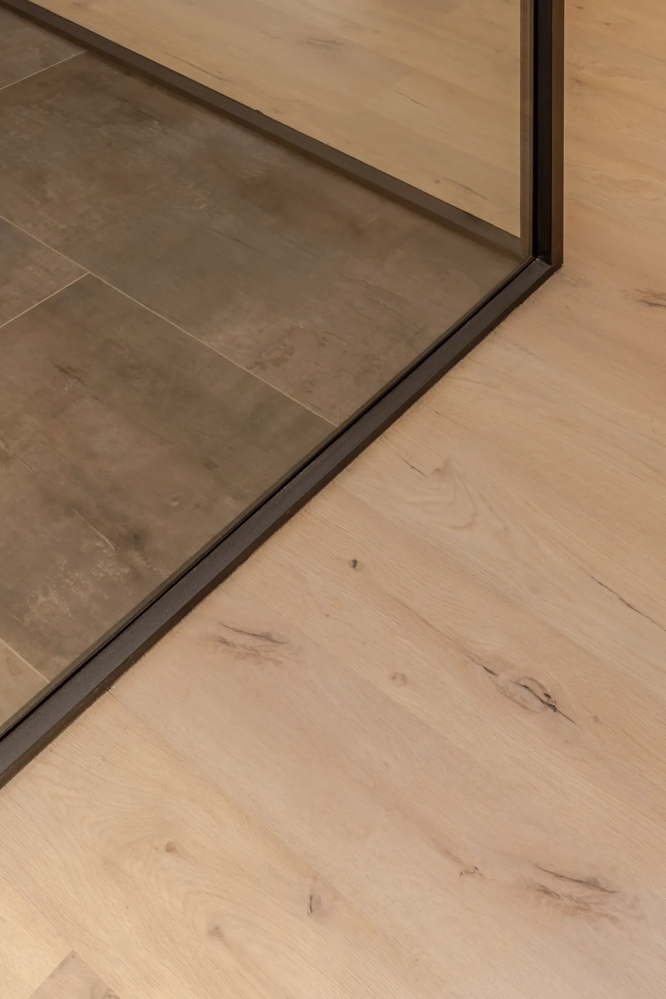 Close-up of light wood and dark tile flooring transition