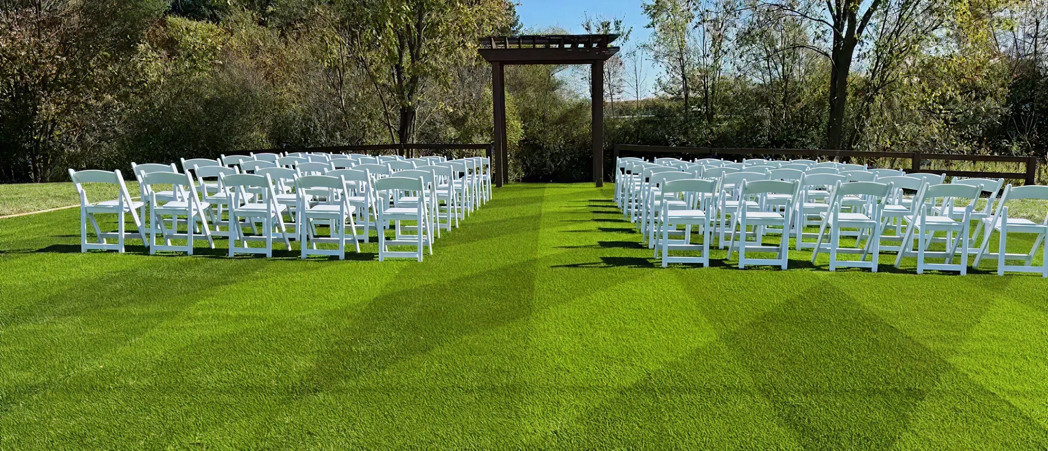 Outdoor wedding ceremony setup with white chairs on manicured artificial turf lawn