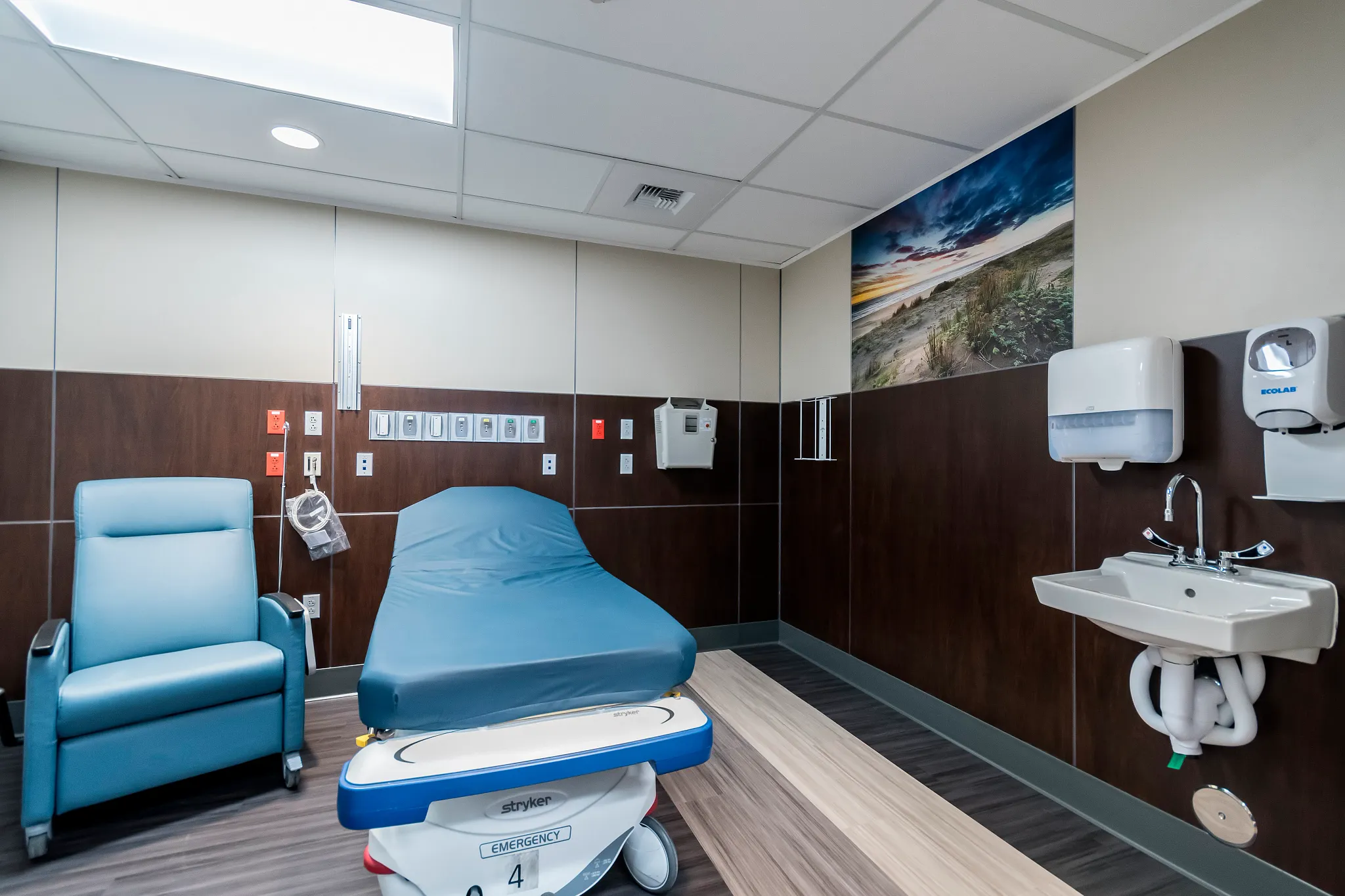 Healthcare facility room with heavy commercial luxury vinyl tile flooring in a 36x9 inch dimension, featuring a blue chair and medical bed