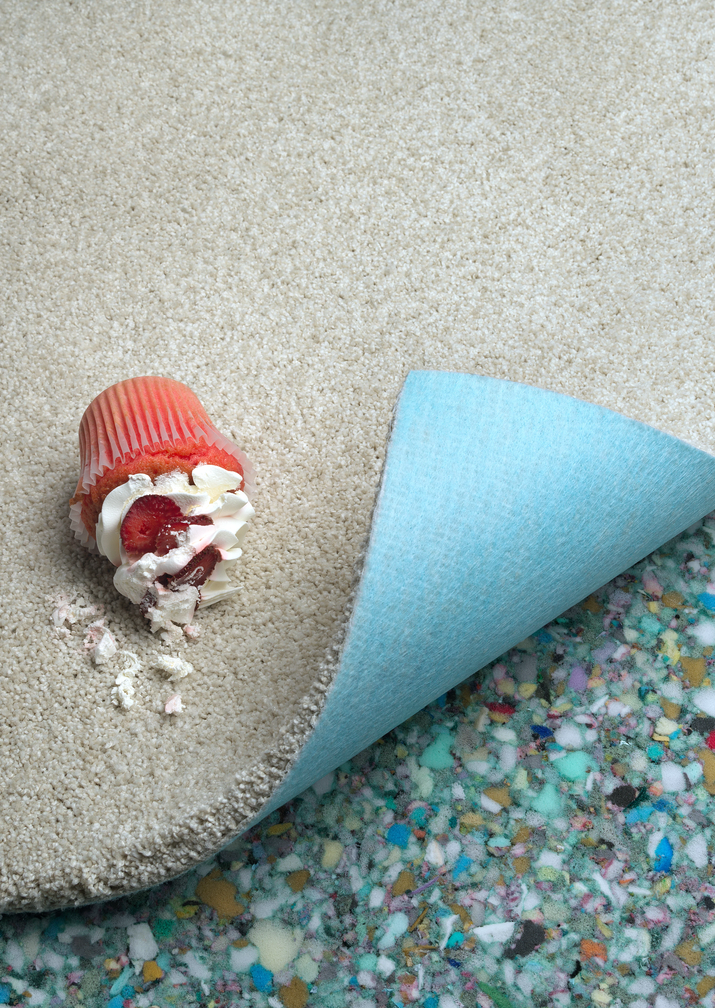 Dropped cupcake on a crem carpet and padding reveal underneath
