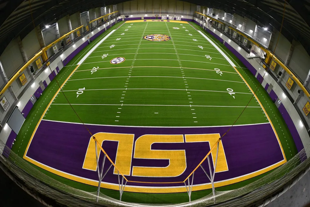 Indoor sports facility with artificial turf featuring LSU logo in purple and gold