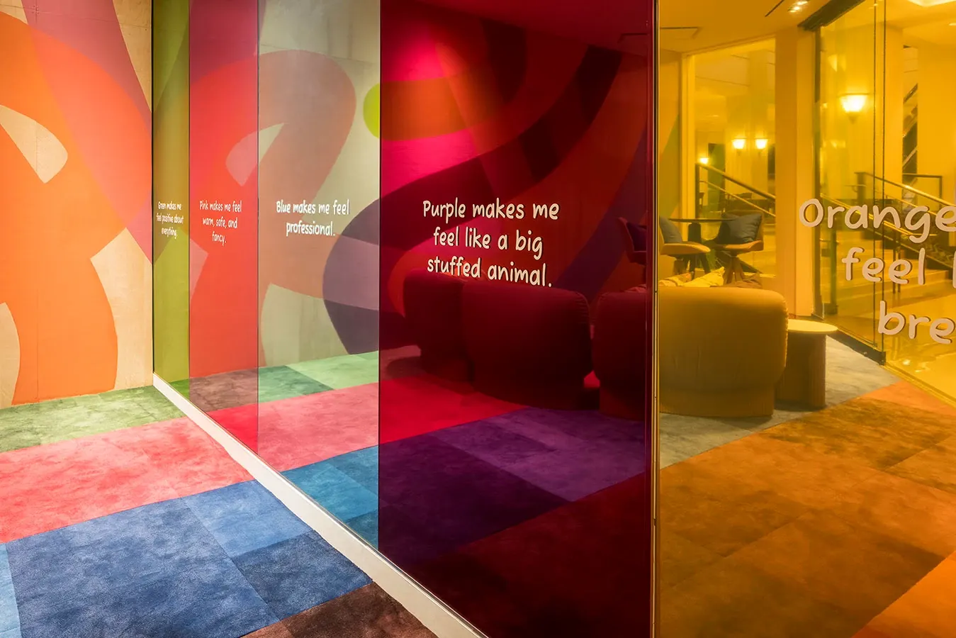 corridor with a glass mirror, green carpet tile, pink carpet tile, blue carpet tile, and purple carpet tile