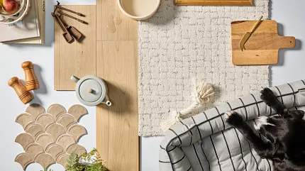 Light Wood Laminate Flooring and Beige Patterned Carpet for Comfortable Living Spaces Cozy home scene with light wood laminate flooring, beige patterned carpet, and a black dog resting on a striped cushion