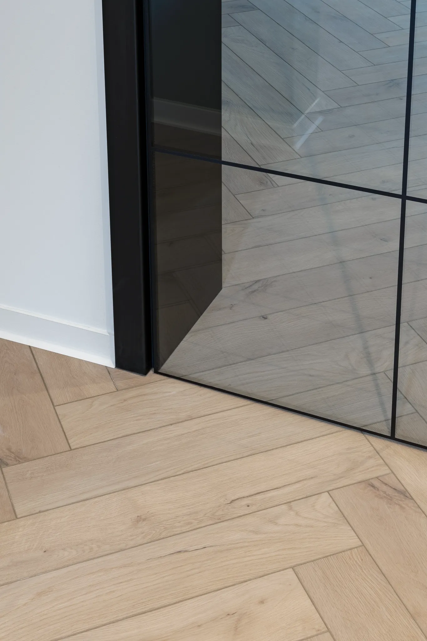Waterproof wooden herringbone floor from Coretec with glass black steel door