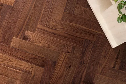 Elegant Herringbone Hardwood Flooring in Rich Brown Tones Herringbone pattern hardwood flooring in rich brown tones with a light wood table and green plant