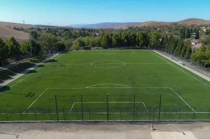 Outdoor soccer field with artificial turf surrounded by nature Aerial view of a large outdoor soccer field with artificial turf surrounded by trees and hills