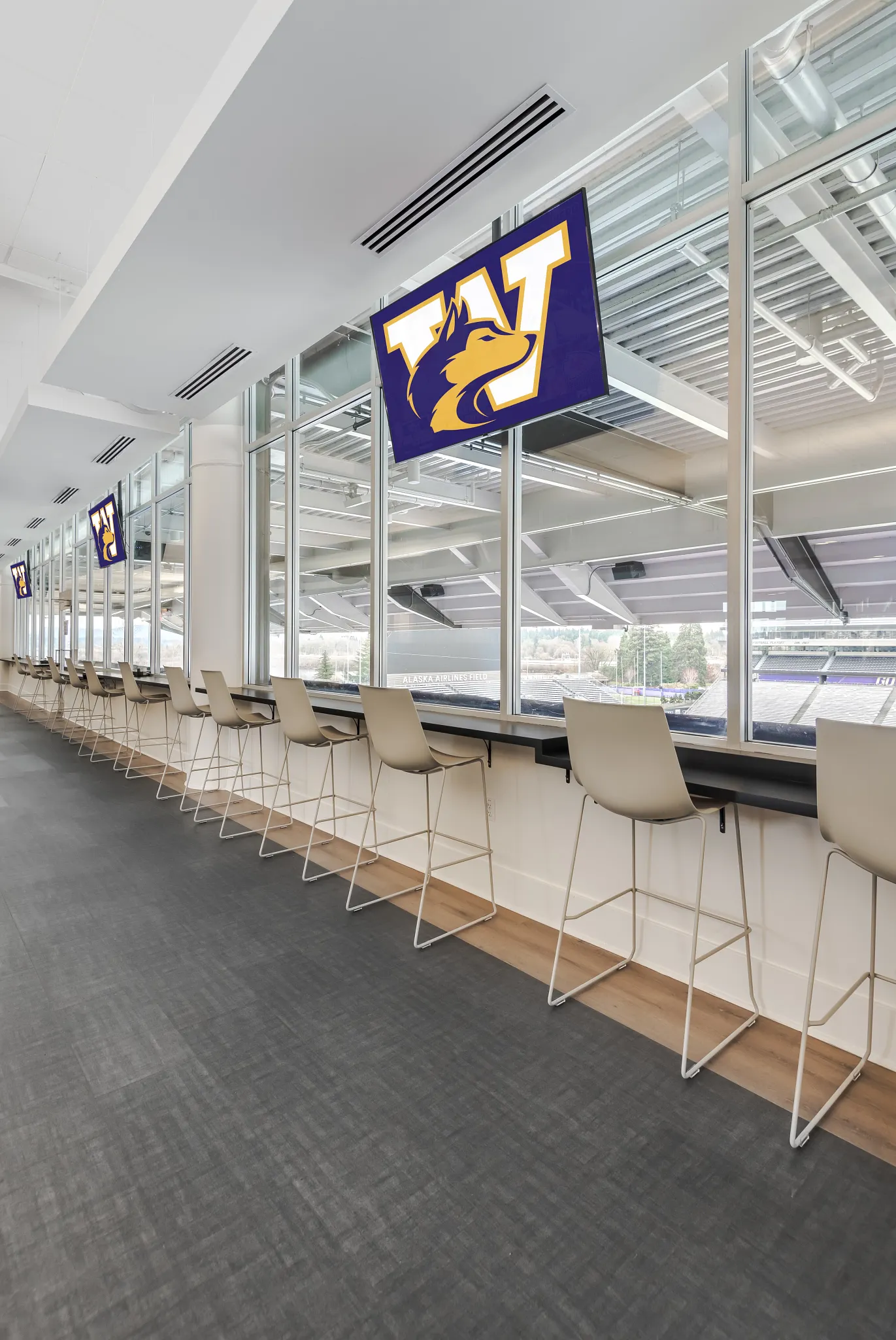 Modern education facility with sleek seating and large windows overlooking a stadium, featuring dark gray commercial flooring