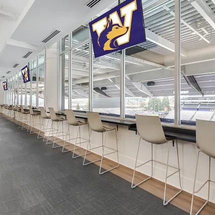Education Facility with Dark Gray Commercial Flooring and Stadium View Modern education facility with sleek seating and large windows overlooking a stadium, featuring dark gray commercial flooring