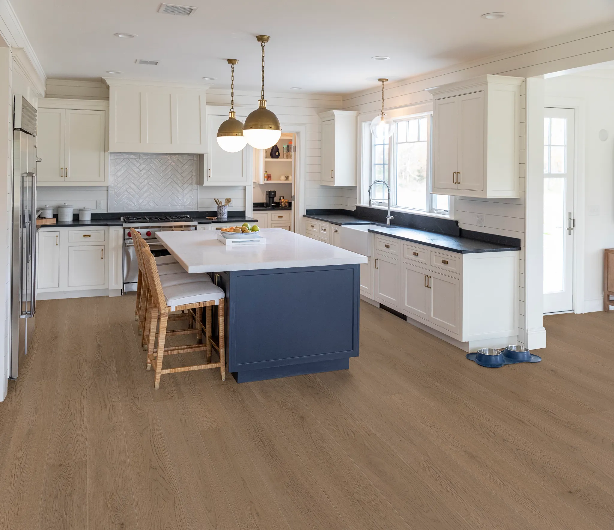 Modern kitchen with light oak hardwood flooring, white cabinetry, and a navy blue island