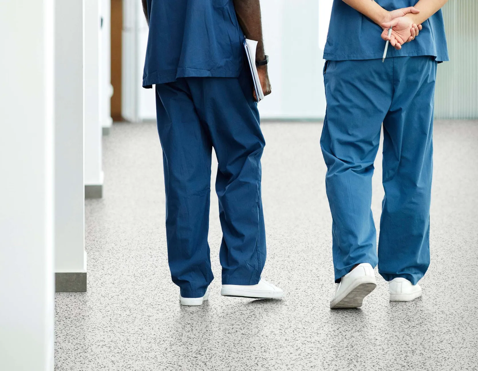 Healthcare professionals walking on speckled commercial flooring in a healthcare facility