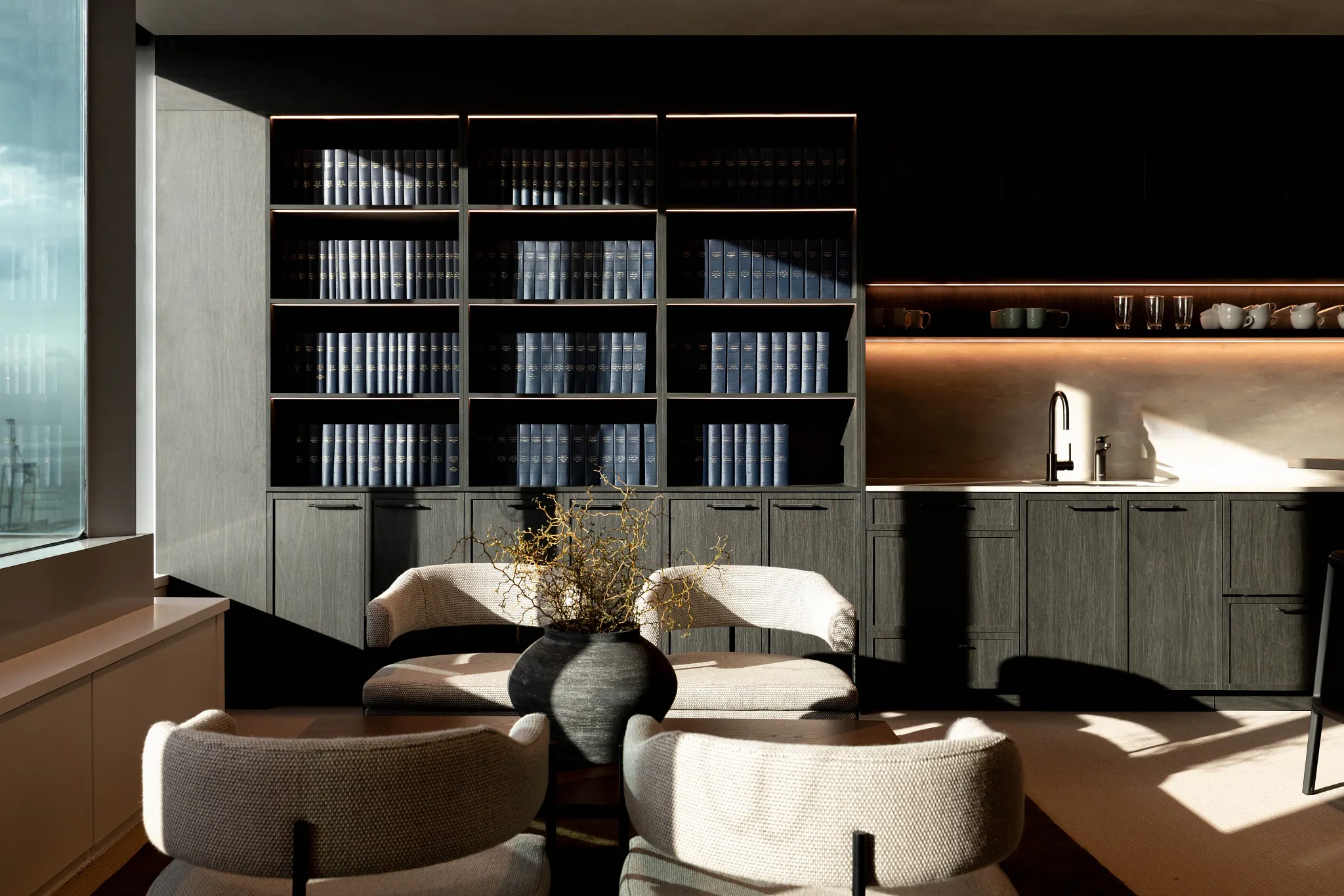 Modern office space with elegant dark wood cabinetry and plush seating