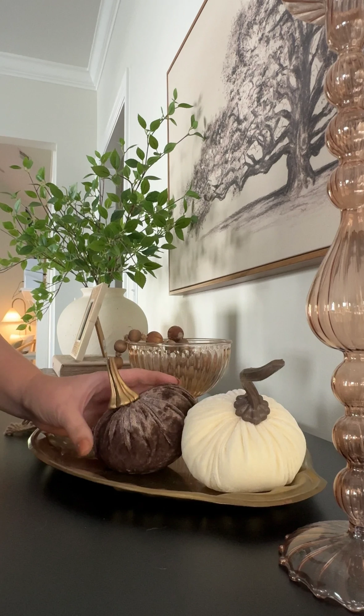 Elegant living room decor with a hand arranging decorative pumpkins on a table