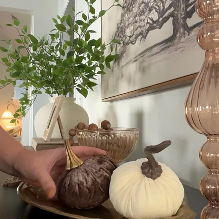 Stylish living room with decorative accents and modern design Elegant living room decor with a hand arranging decorative pumpkins on a table