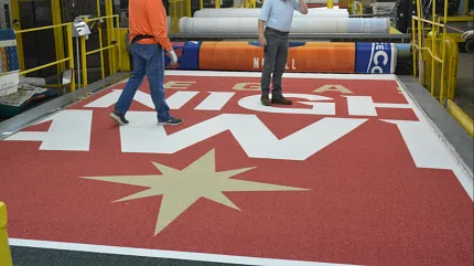 Custom carpet manufacturing process with bold design Large custom carpet with red and gold design in factory setting