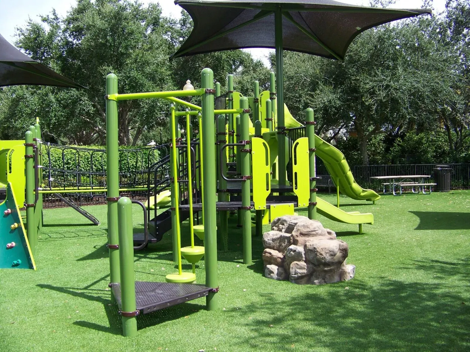 Green playground equipment on artificial grass surface